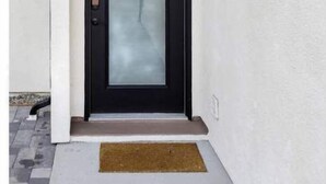 A modern black door with a frosted glass panel, a black metal light fixture above, and a brown doormat at the entrance. - NoHo Toluca Lake Luxury Near Universal Studios  (Los Angeles)
