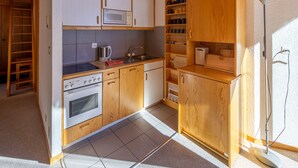A kitchen with wooden cabinets, a microwave, an oven, and a sink.