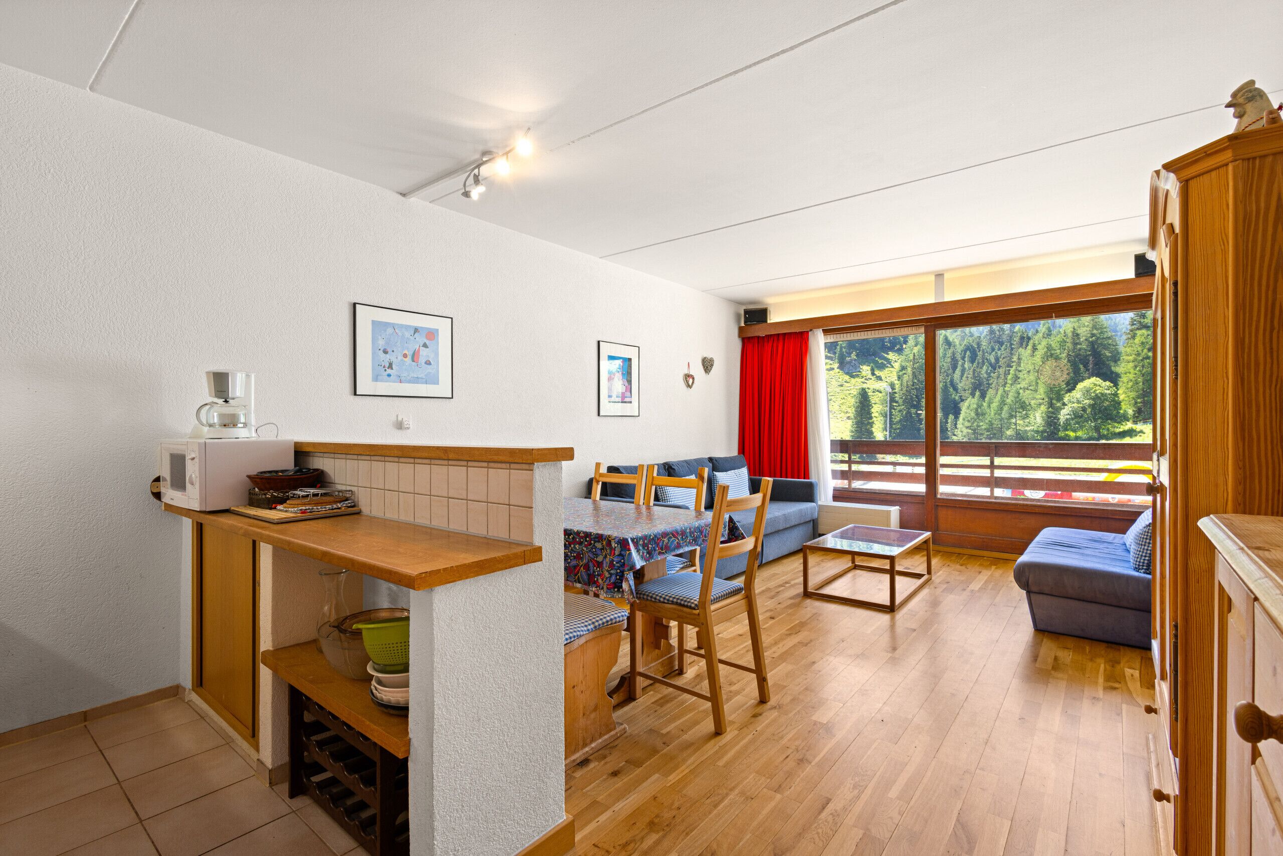 Sala de estar con sofá, una mesa de comedor y una zona de cocina con microondas.