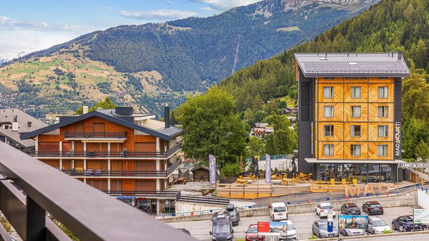 Ein Hotel mit Holzfassade und ein modernes Gebäude mit dem Schild 'MADMWITT'.