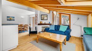 Ein gemütliches Wohnzimmer mit Holzboden, einer Couch, einem Couchtisch und einem Essbereich mit Stühlen und einem Tisch.