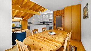 Eine moderne Küche mit weißen Schränken, einem Holztisch und einem blauen Stuhl.
