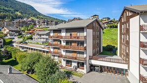 Un hôtel à plusieurs étages doté de balcons, d’un parking et offrant une vue sur un paysage montagneux.