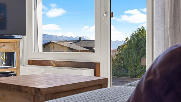 Une pièce avec une grande fenêtre, une table en bois et un téléviseur.