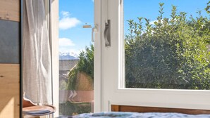 Une chambre à coucher avec un lit, une fenêtre et une vue sur la verdure et les montagnes.