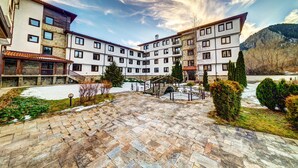 Un hotel de varios pisos con patio, sendero de piedra y abundante vegetación.