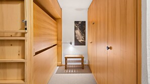 A wooden closet with a bench, a door, and a poster on the wall. - Les Hauts-de-Nendaz B L7 - 4 pers - ski In/Out (Haute-Nendaz)