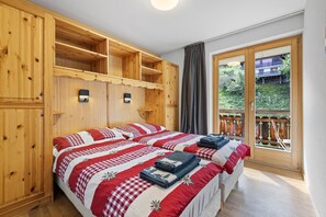 A room with a large bed, wooden cabinets, and a sliding glass door to a balcony.