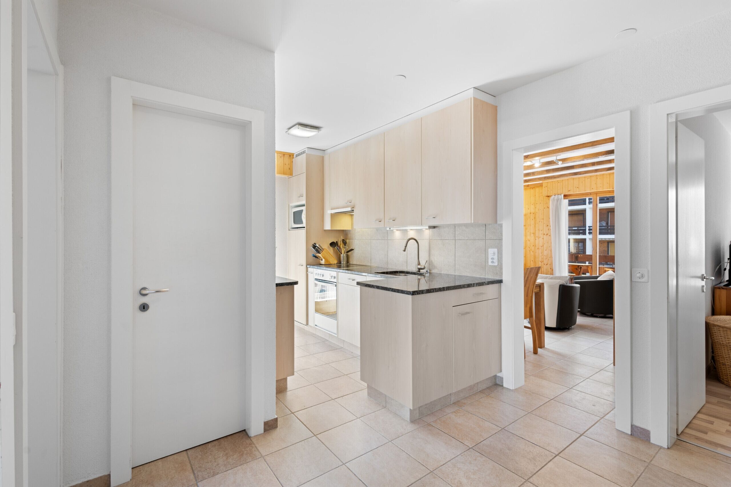 Een moderne keuken met lichte houten kastjes, een centraal eiland en een ingebouwde oven.