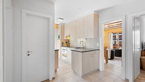 A modern kitchen with light wood cabinets, a central island, and a built-in oven. - Le Torrent 26 - 6 pers - au calme (Haute-Nendaz)