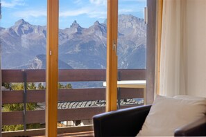 Une pièce avec vue sur les montagnes, grâce à de grandes fenêtres.