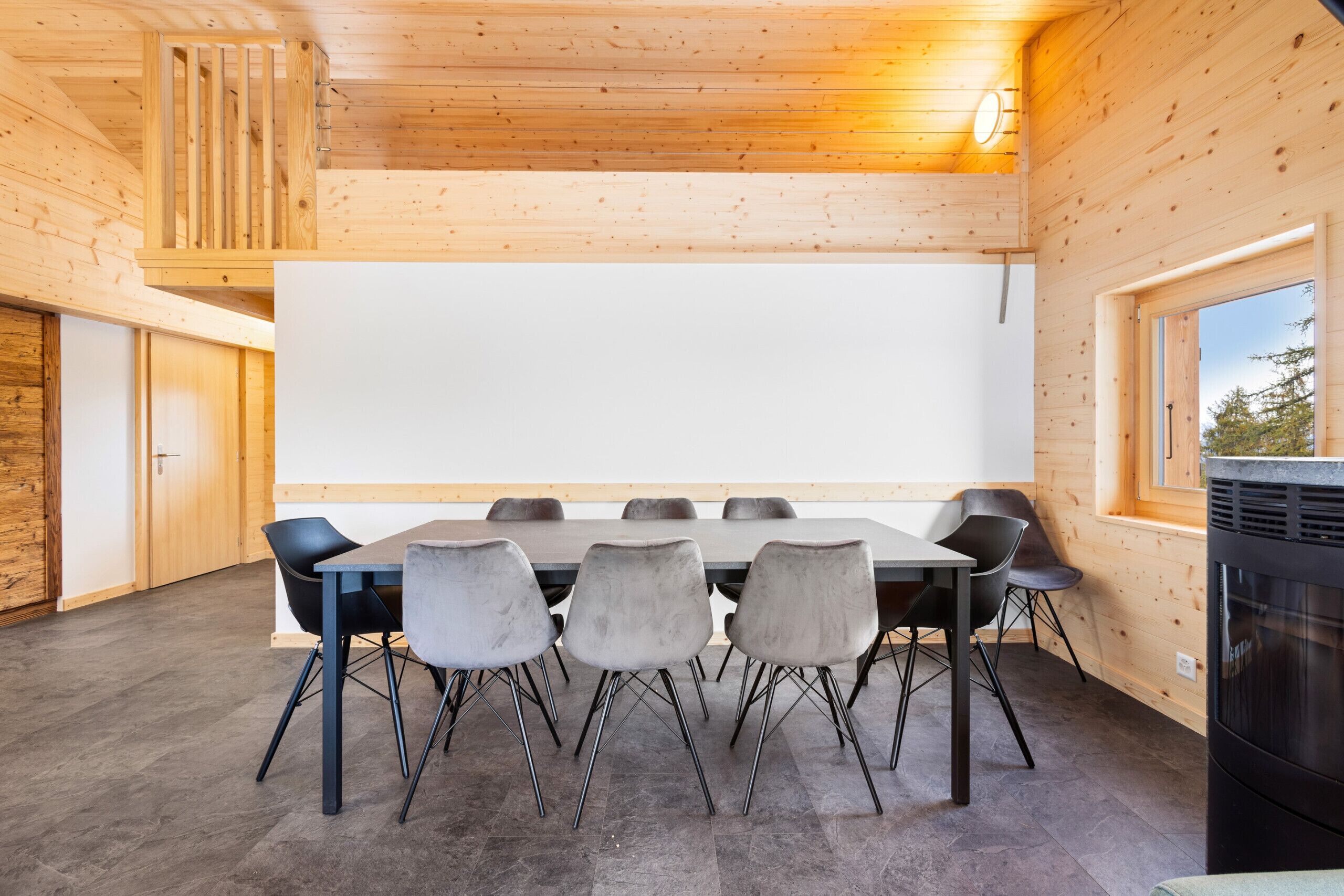 Ein moderner Konferenzraum mit einem langen Tisch, sechs Stühlen, einer Tafel und einem Kamin.