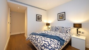A bedroom with a bed, two bedside lamps, and two framed pictures on the wall. - Modern apartment in fantastic Central London (London)