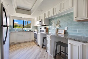 A modern kitchen with white cabinetry, a large window, and a view of the outdoors. - Soak in the Sun in New Smyrna Beach ★ Family Friendly Retreat ★ Short Walk (New Smyrna Beach)