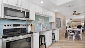 A modern kitchen with white cabinets, stainless steel appliances, and a granite countertop.
