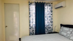 Una camera da letto con un letto, una porta e una finestra con tende.