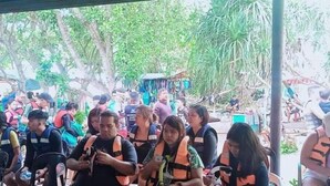 Un gruppo di persone sedute all'aperto, alcune con giubbotti di salvataggio, probabilmente impegnate in un'attività ricreativa o legata alla sicurezza.