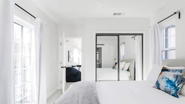 A modern hotel room with a large bed, a wardrobe, and a bathroom visible through a glass door.