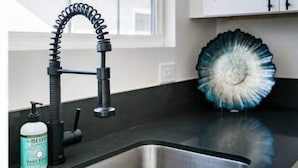 A modern kitchen with a stainless steel sink, a black faucet, and a decorative blue and white plate on the counter.