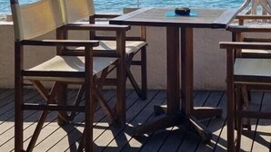 A wooden deck with tables and chairs, overlooking a body of water with mountains in the background. - Modern apartment Oleandra, 5 only 250 meters from the sea (Baska)