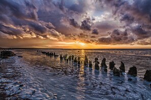 A sunset over a beach with rock formations in the water. - Huize Moddergat! Slapen aan de Voet van de Waddenzee (Moddergat)