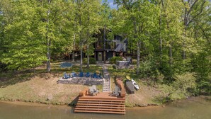 A lakeside cabin with a deck, outdoor seating, and a boat. - A Shore Thing by Innsbrook Vacations! (Innsbrook)