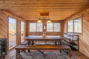 A wooden interior with a large table, benches, and a hanging light fixture. - A Shore Thing by Innsbrook Vacations! (Innsbrook)