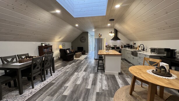 A spacious loft with a high ceiling, a skylight, a kitchen, a dining area, and a living room. - Peaceful country getaway close to Cooperstown NY (Oneonta)