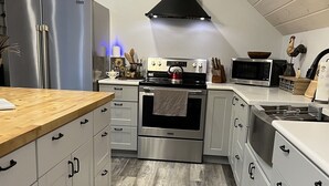 A modern kitchen with white cabinets, stainless steel appliances, and a decorative rug. - Peaceful country getaway close to Cooperstown NY (Oneonta)