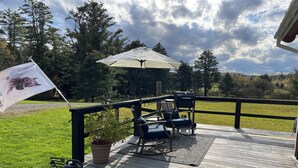 A wooden deck with outdoor seating, a grill, and a flag. - Peaceful country getaway close to Cooperstown NY (Oneonta)
