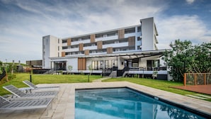 A modern hotel with a swimming pool, outdoor seating, and a covered patio area. - Tyne Aparthotel l Steam Room l Pool (Cape Town)