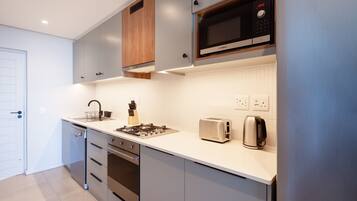 A modern kitchen with grey cabinets, a Bosch microwave, a toaster, and a kettle.