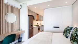 Quarto moderno com cama grande, escrivaninha e bancada de cozinha.