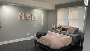 Een slaapkamer met een bed, een raam met zonwering en decoratieve muurkunst.