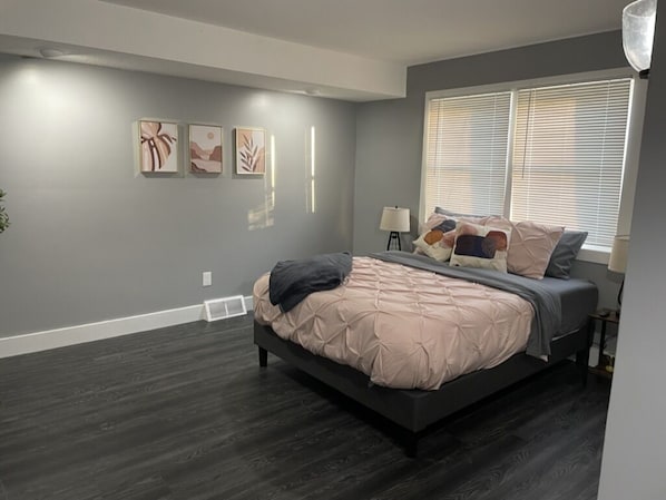 Un dormitorio con cama, ventana con persianas y decoración en la pared.