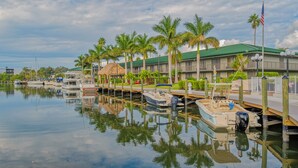A marina with boats docked, a building with a green roof, and palm trees. - ALL-NEW Waterfront with Balcony, Pool, Tiki Bar, Gym (Sarasota)