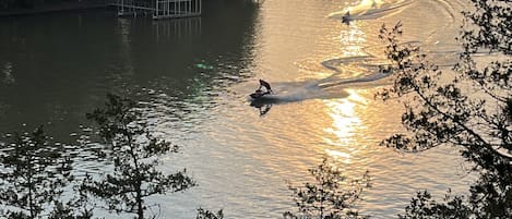 En flod med en båd, der efterlader et spor i vandet, omgivet af træer og en bro.