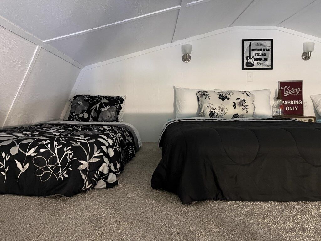 A bedroom with two beds, floral-patterned bedding, a 'Victory' sign, and a 'Music to what you're feeling' poster.