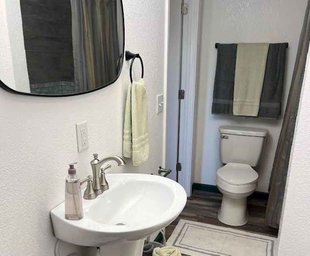 A bathroom with a white sink, a mirror, and a toilet.
