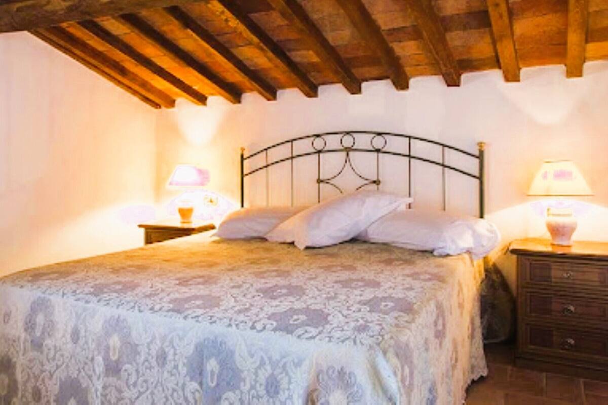 Un dormitorio con una cama, dos mesitas de noche y techo de madera.
