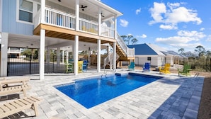 A two-story house with a swimming pool, outdoor seating, and a covered patio area. - Poolside Getaway Near the Beach (Port Saint Joe)