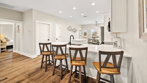 A modern kitchen with a central island, wooden chairs, and a dining area. - Poolside Getaway Near the Beach (Port Saint Joe)