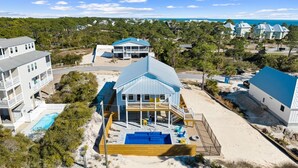 A beachfront property with a large house featuring a blue roof, a swimming pool, and a view of the ocean. - Poolside Getaway Near the Beach (Port Saint Joe)