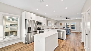 A modern kitchen with white cabinetry, stainless steel appliances, and a central island. - Poolside Getaway Near the Beach (Port Saint Joe)