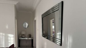Un couloir doté d’un sol en marbre, d’un canapé avec des coussins, d’un miroir et d’une table avec une lampe.