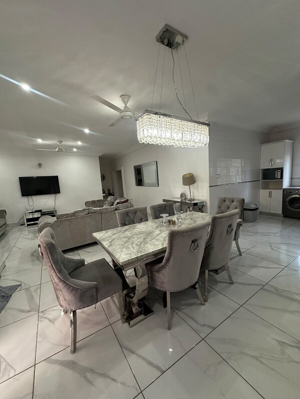 A modern dining area with a marble table, upholstered chairs, a chandelier, and a ceiling fan. - Luxury Spacious two bedroom apartment for comfortable living. Well furnished . (Banjul)