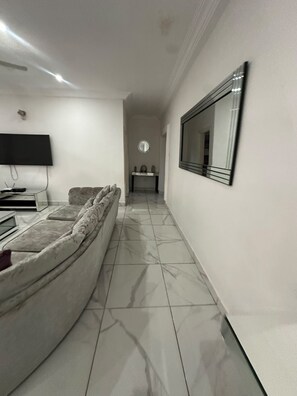 Un salon moderne avec un canapé, un téléviseur à écran plat, une console et un miroir.