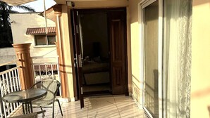Un balcon doté d’un sol carrelé, d’une table avec des chaises et d’une porte-fenêtre coulissante donnant sur un espace intérieur.