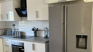 Une cuisine moderne avec des armoires blanches, des appareils en acier inoxydable et un sol en marbre.