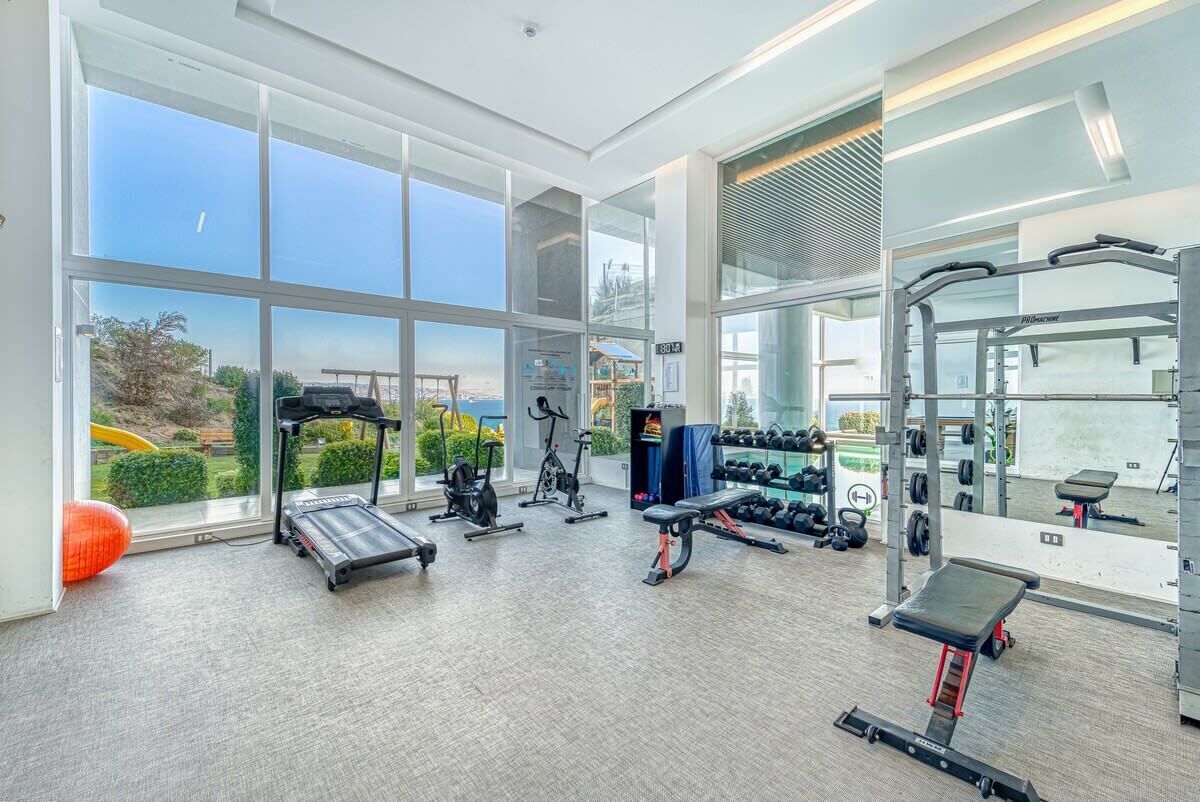 A gym with cardio machines, free weights, and a bench.
